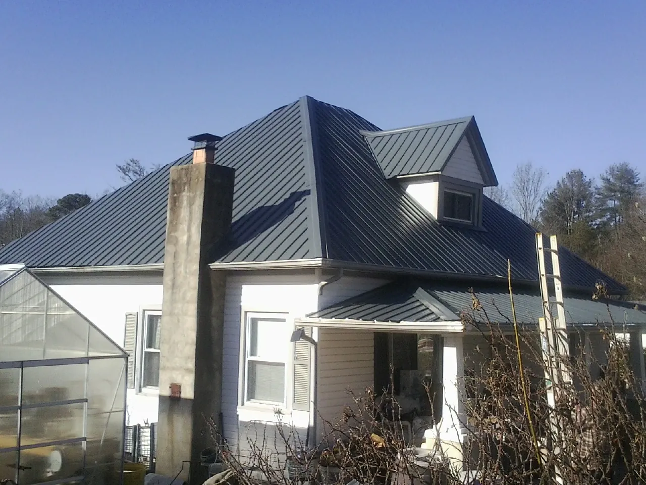 Dark blue standing seam metal roof on a white farmhouse with dormer — Slate & Tile Roof Repair by Roofing Brothers in Poulsbo