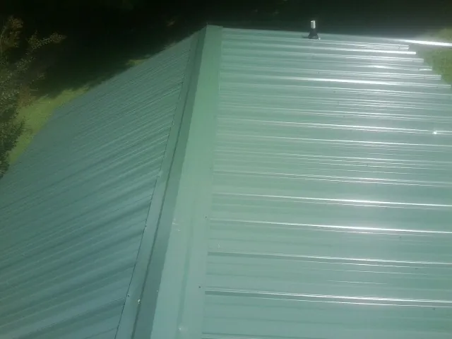 New green metal panels meeting at the ridge of a roof — Flat Roof Repair work by our crew in Poulsbo