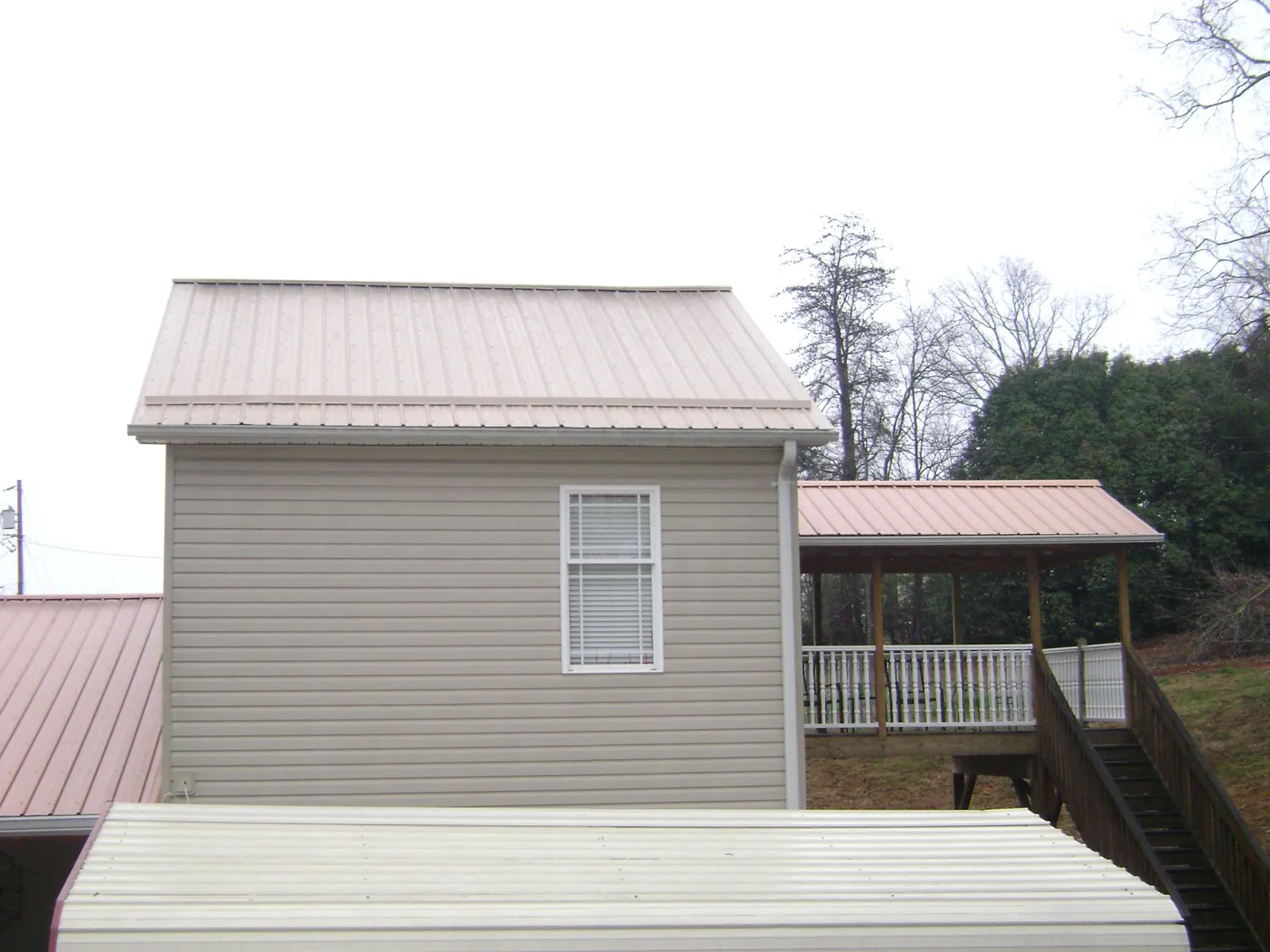 Tan metal roofs on a two story addition and attached porch, from a Roof Replacement job in Poulsbo