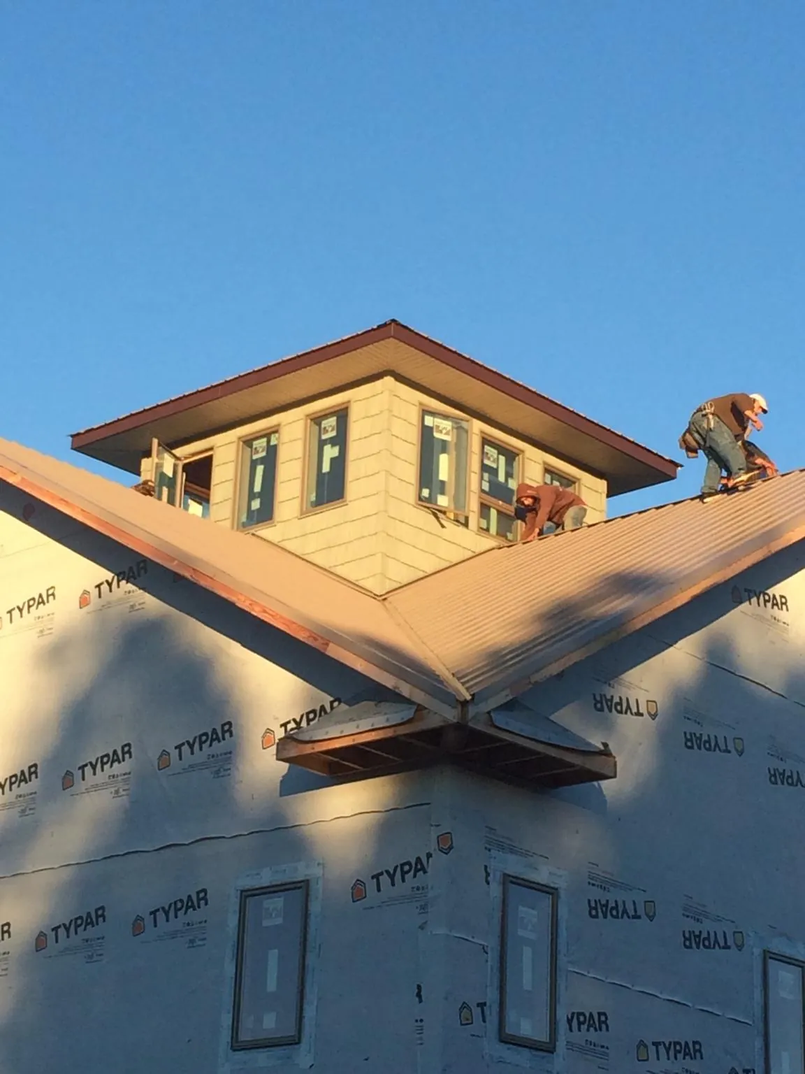 Roofers working around a rooftop cupola on a new metal roof at sunset — Roof Waterproofing in Poulsbo by Roofing Brothers